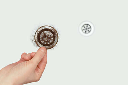 Drain hole in the bathroom. Drain filter with a tuft of hair in hand.の写真素材