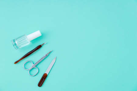 Manicure tool kit and nail polish. Turquoise background.