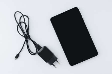 Black smartphone and charger. white background.