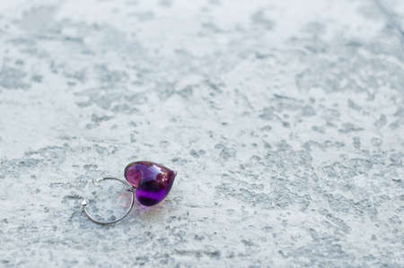 Wine glass pendant in the shape of a heart. Shabby concrete background.