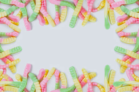 Frame of bright colored chewing candies in the form of worms. white background. Place for text.の写真素材