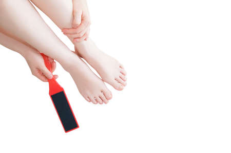 Pumice stone for feet in the hands of a caucasian woman. Women's legs.Feet skin care concept.