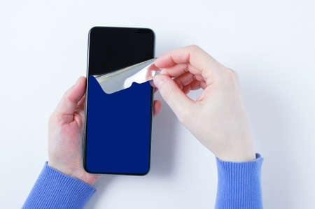 Removes the protective film from a new smartphone. white background.