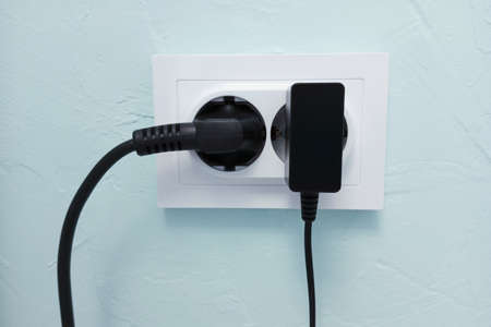 White electrical socket on the wall with electrical appliances turned on.