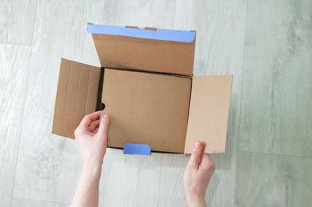 Unpacking the goods from the box. The woman hand opens the box.
