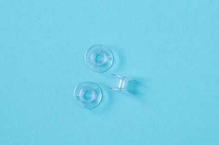 Plastic transparent bobbins for a sewing machine. blue background.