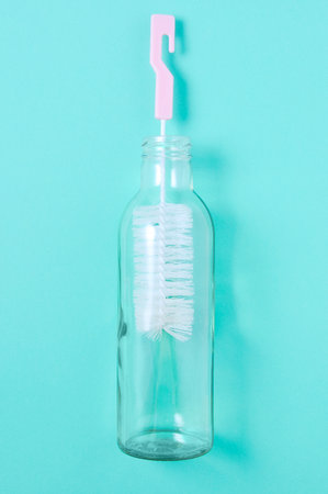 bottle cleaner and glass bottle. green background.