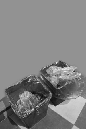 Two trash cans with polyethylene against the background of the room wall. Black and white photo.の写真素材