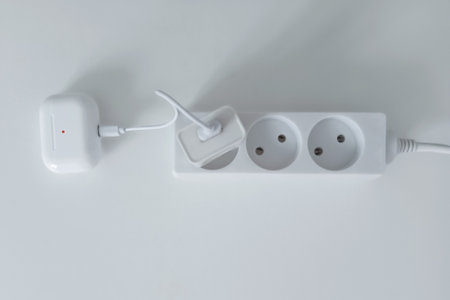 Charging case for wireless headphones with USB cable plugged into an electrical outlet.