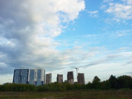 House under construction on a field in summer daytime against the background of the sky with clouds.