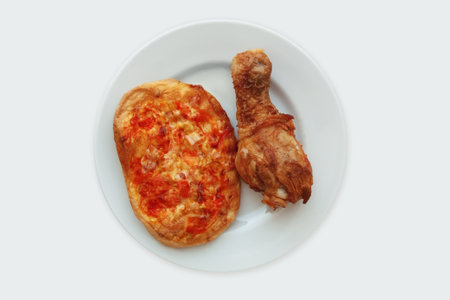 Mini pizza and fried chicken thigh on a white plate. White background.の写真素材