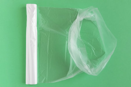 Transparent polyethylene bags in an unrolled roll. Green background.