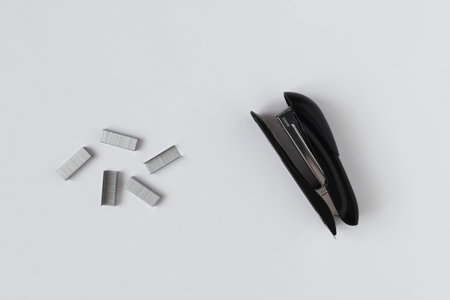 Black office stapler and metal staples for the stapler. White background.の写真素材