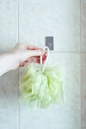 Hanging a body washcloth on a hook in the bathroom tile background.の写真素材