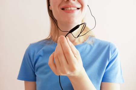 Black headset microphone and headphones in hand of young Caucasian woman. Smiling speaks into...