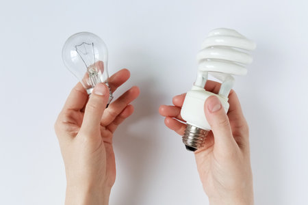 Incandescent lamp and energy saving lamp in hands of Caucasian woman. Concept energy resources....