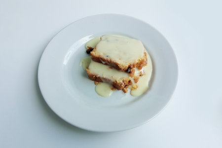 Sliced pieces of biscuit on a white plate covered with white cream.