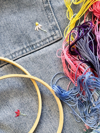 Embroidered flowers on fragment of blue denim jeans texture