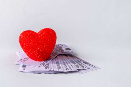 red heart and money on a white background. The concept of love and business.の写真素材