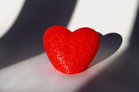 red heart on a white background with its own shadow. valentine's day. The concept of the symbol of loveの写真素材