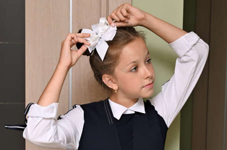 Close-up portrait of pretty girl with white bow in her hair and beautiful school uniform. First day of school. Back to schoolの写真素材