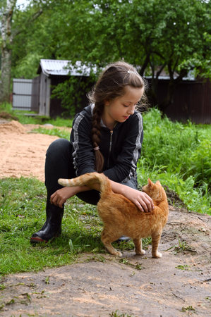 beautiful girl strokes a red cat on a sunny summer day. The concept of love and care for a petの写真素材