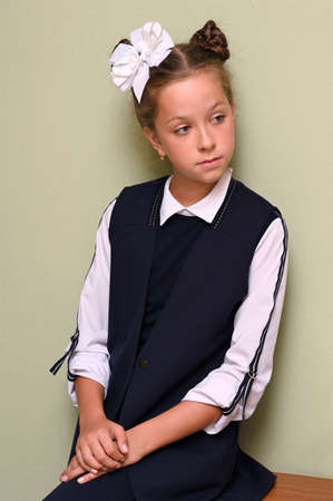 Portrait of pretty girl with white bow in her hair and beautiful school uniform. The first day of...