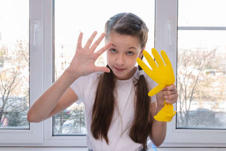 girl in yellow house gloves cleans the window of the house. Cleaning concept.の写真素材