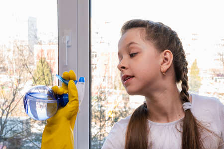 girl in yellow house gloves cleans the window of the house. Cleaning concept.