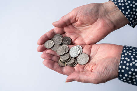 Close-up of an elderly woman's hand counting money, isolated on white background. Pension savings, home financeの写真素材