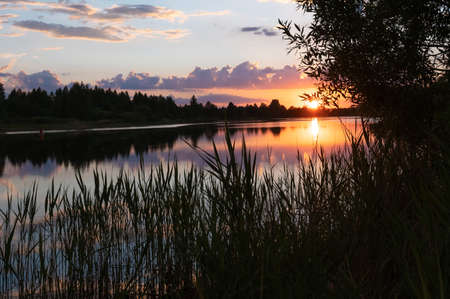 Beautiful summer sunset and colorful sky over the river. Clouds are reflected in the water. Beauty in this worldの写真素材