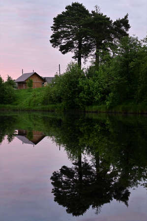 Sunrise over river with pink clouds in sky, reflected in calm water. Picturesque early morning. Creative images with mirror image. Vertical photo. Concept of nature, summerの写真素材