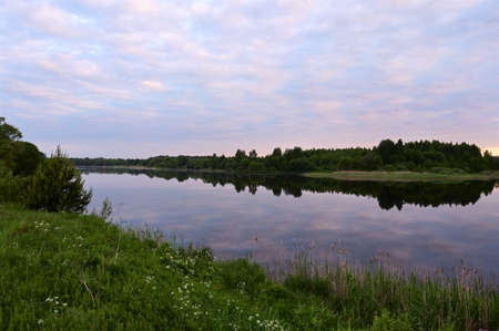 wonderful sunrise over river with pink clouds in sky, reflected in calm water. Picturesque landscape in early morning. Concept of nature, summer, travel and seasons. Copy spaceの写真素材