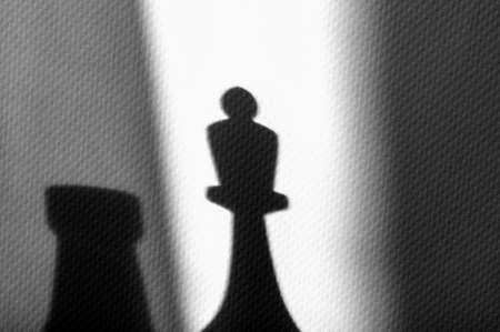Dark shadows from chess pieces on a white background. Evening game of shafmati with a friendの写真素材