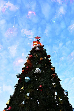 Christmas tree decorated with toys on blue sky background. Photo was taken in multi-exposure modeの写真素材