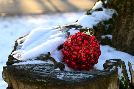 Red Christmas ball toy lying on the snow. Preparing for New Year, decorating the Christmas tree. Festive moodの写真素材