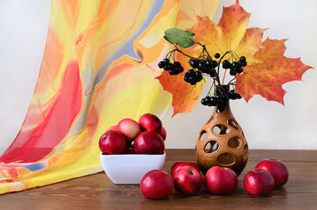 beautiful autumn bouquet of orange maple leaves, chokeberry and red apples on wooden table. Colorful nature. Harvest timeの写真素材
