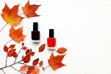 Beautiful autumn layout of orange leaves and nail polish on white background. Flat layout with top view. Copy space. Concept of autumn makeupの写真素材