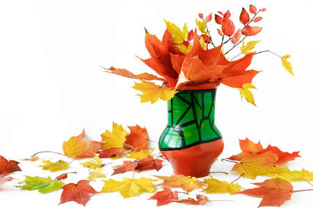 beautiful bouquet of yellow and orange maple leaves in ceramic vase on white background. Bright colors of autumnの写真素材
