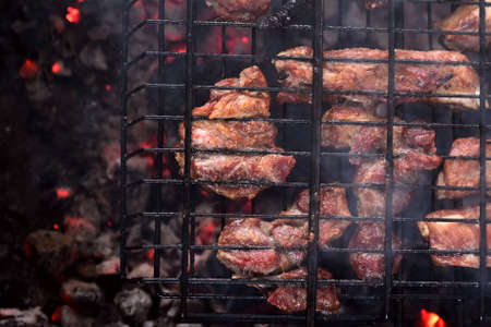Delicious crispy meat barbecue on metal grill in open air. Cooking meat on grill in nature in summer on picnic. Grilled pork, close-up. Flat lay with top viewの写真素材