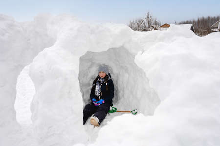 teenage girl plays with snow on a winter day and builds a snow fortress in the open air. Winter...