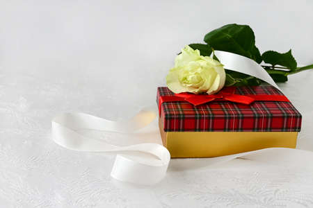 Beautiful white rose and red gift box on white silk background. Congratulations on Valentine's Day, happy birthday. Copy spaceの写真素材