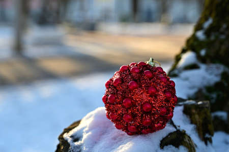 Red Christmas ball toy lying on the snow. New Year's mood. Close-up
