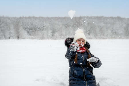 Beautiful happy girl playing snowballs, laughing and having fun with snowの写真素材