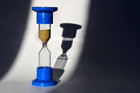 An hourglass on a white background with its own shadow. The concept of the transience of time