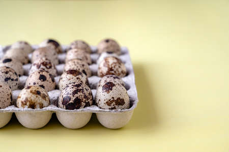 quail eggs in cardboard box on yellow background. close-up. The idea of healthy breakfast, symbol of Easter. copy spaceの写真素材
