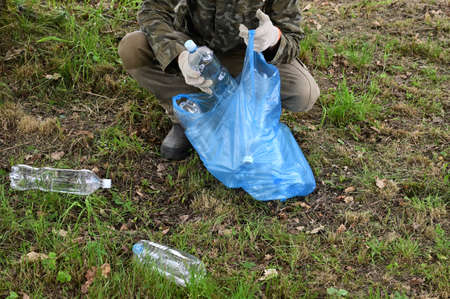 Human picking up plastic bottles in garbage bag. Protection of nature, ecology from pollution. World...