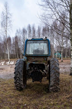 blue tractor among trees outdoors on farm without driver. Development of agriculture. agricultural...
