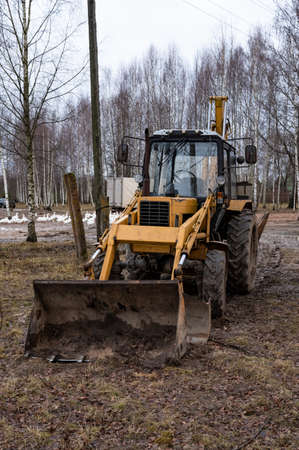 yellow tractor among the trees in the open air on a farm without a driver. front view. agricultural...