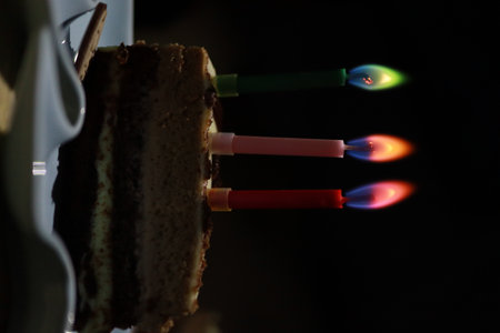 birthday cake with burning candles on a black background, close-upの写真素材